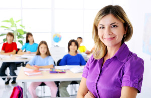 Female teacher standing on the foreground in a class room.