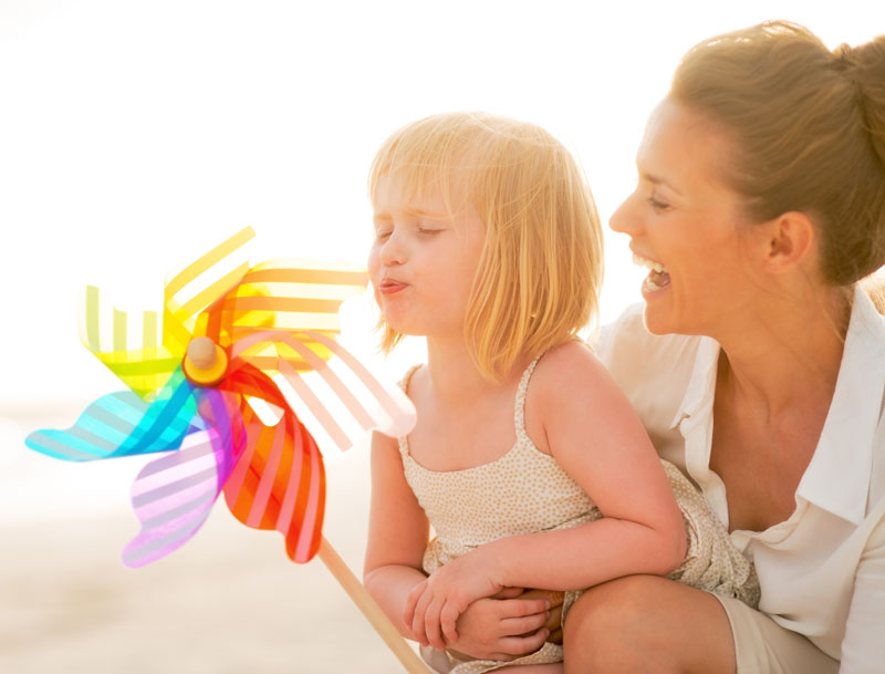 Child and Mother Blowing On Colorful Pinwheel